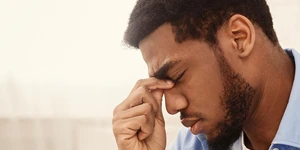 Man holding nose in pain