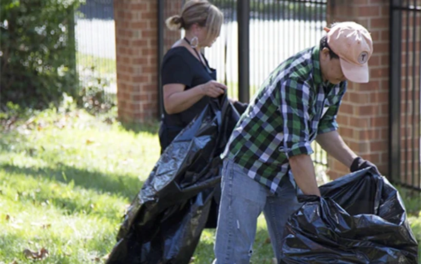 Two people picking up trash outside